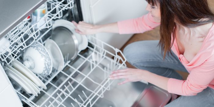A beautiful woman using a dishwasher in a modern kitchen. domest